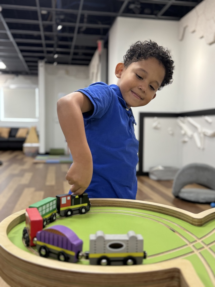 A child plays with a wooden train set