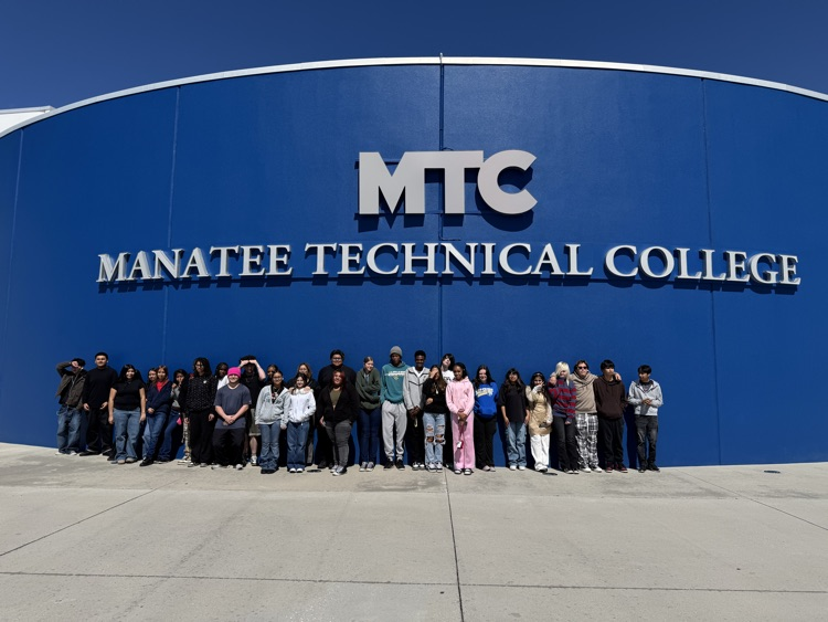 Students lined up in front of a blue building with a sign that reads Manatee technical College