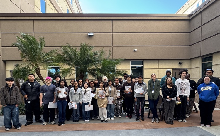 A group of high school students pose for a photo in front of a hospital on a field trip