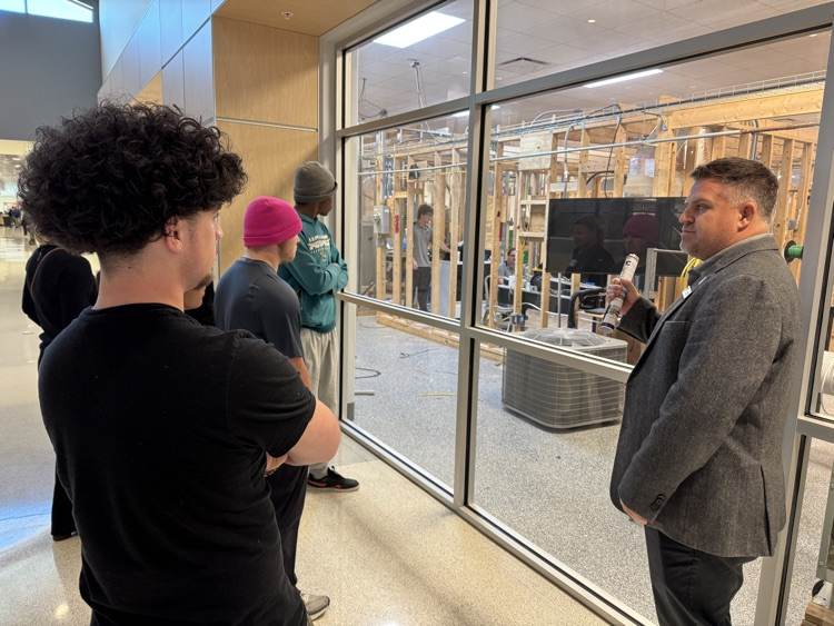 High school students peer into a construction in manufacturing classroom at a technical school