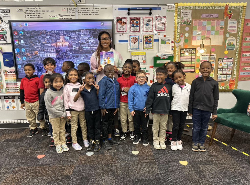 A class of young student surround a guest author in a photo.
