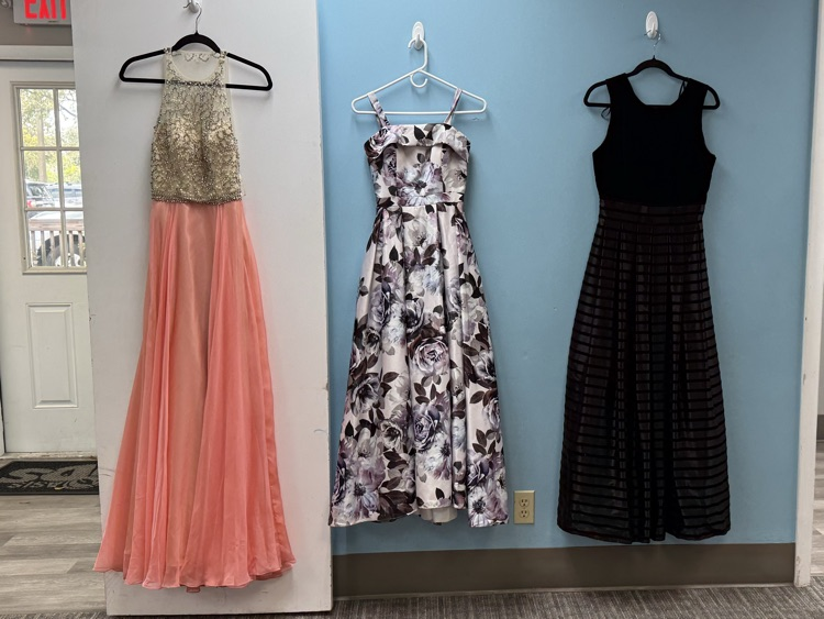 three prom style dresses, hanging on hangers