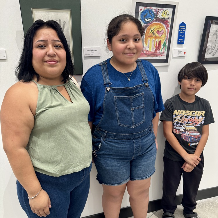 A family stands, proud next to their young artist work, which sold