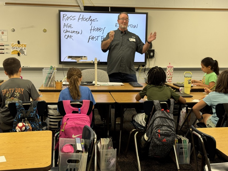 a man standing in front of students giving a presentation 