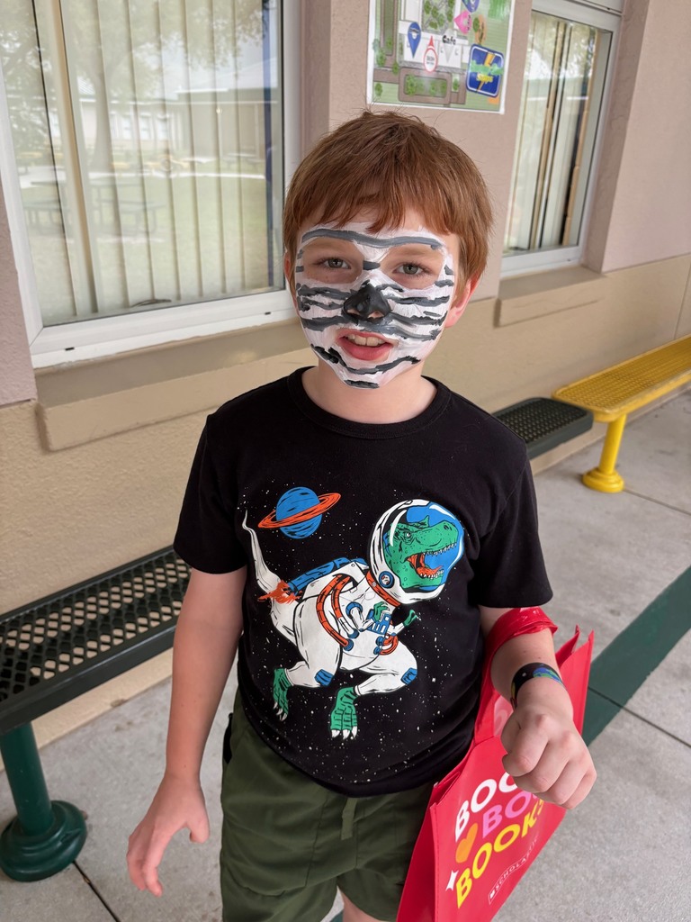 A boy wearing a space themed shirt and his face painted like a planet.