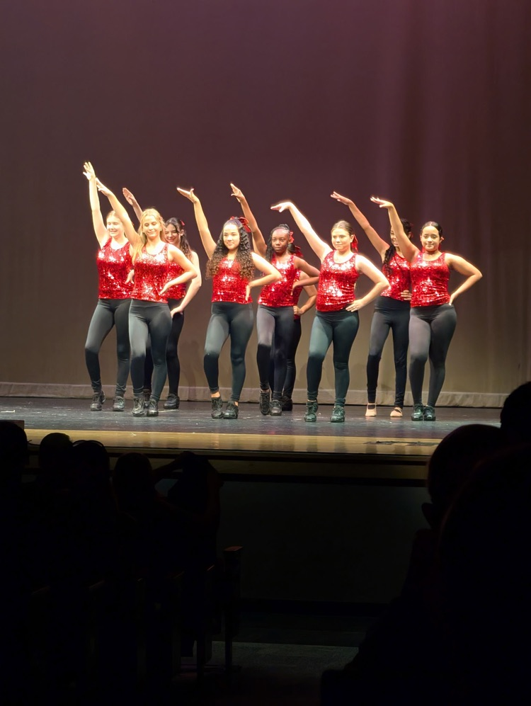dancers wearing red sparkly tops and black pants on stage
