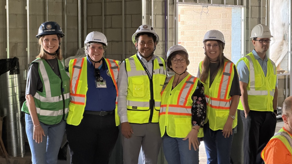 School District personnel wearing hard hats and fluorescent vests at an elementary school under construction. 