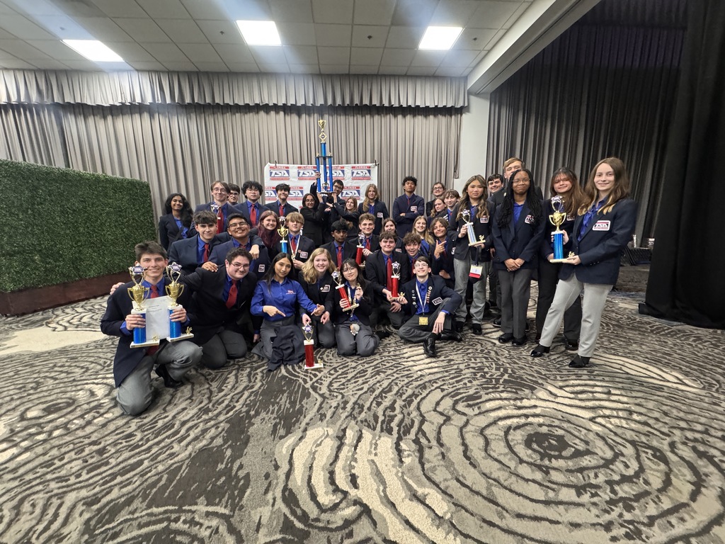 Braden River High School students, dressed in TSA uniforms, hold up their trophies with big smiles on their faces.