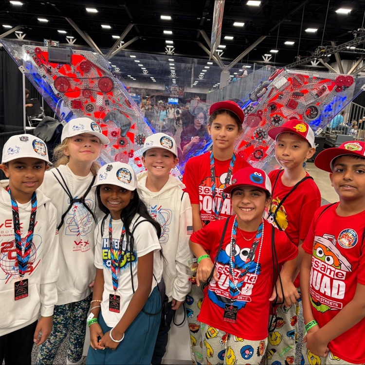 two groups of smiling students, one wearing white shirts, one wearing red shirts