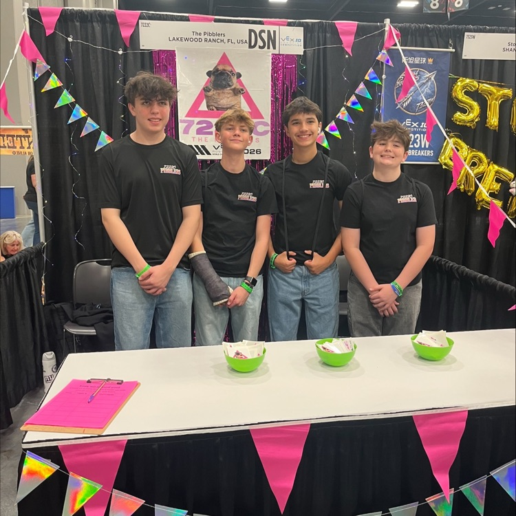 for filing students wearing black shirts, in front of a table, draped and neon flags
