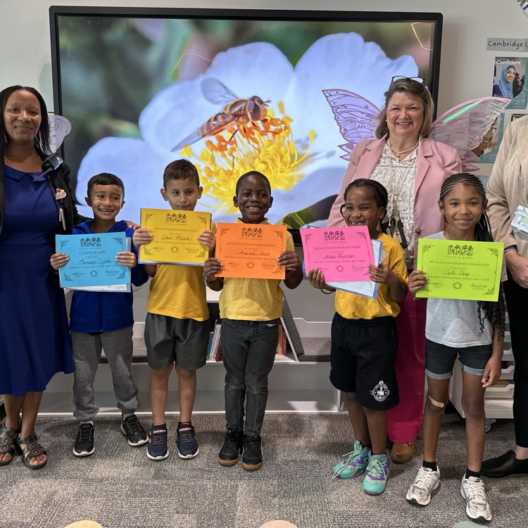 smiling children hold up certificates with their principal and teacher