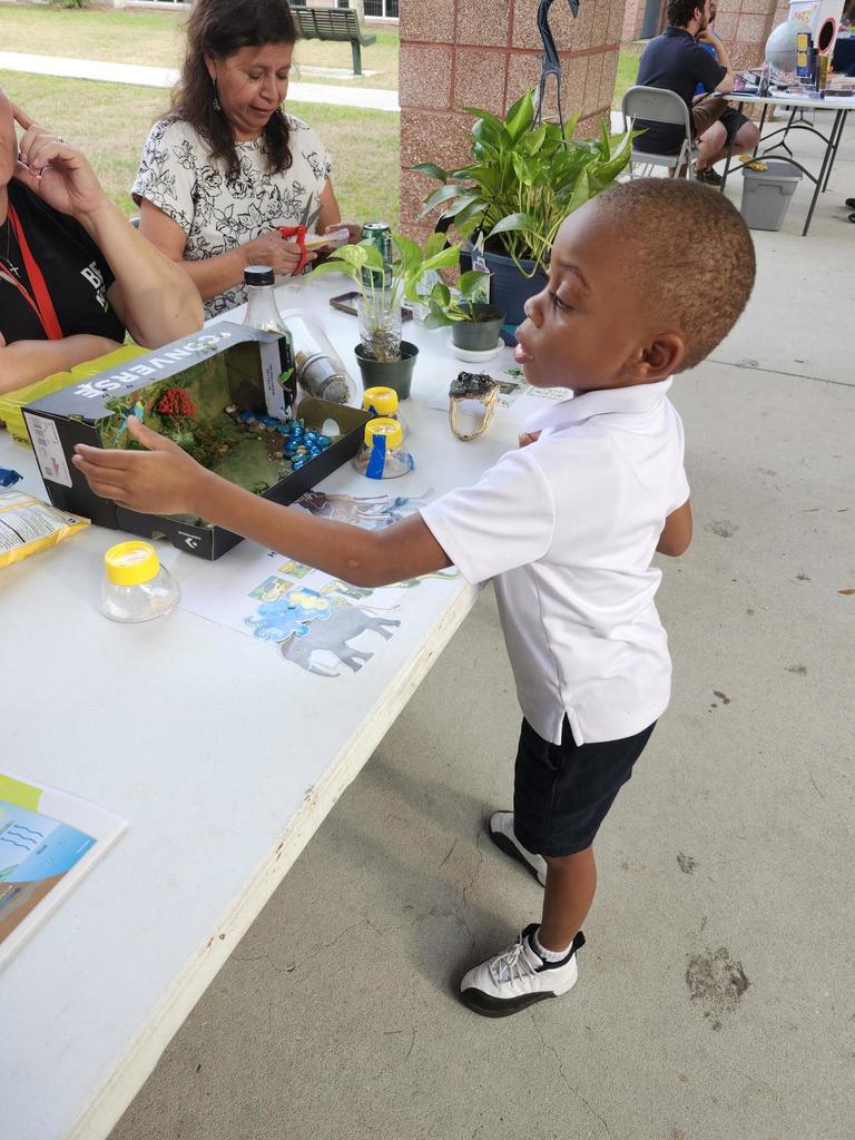 A boy in a white shirt learning during a STEAM Night event at school.