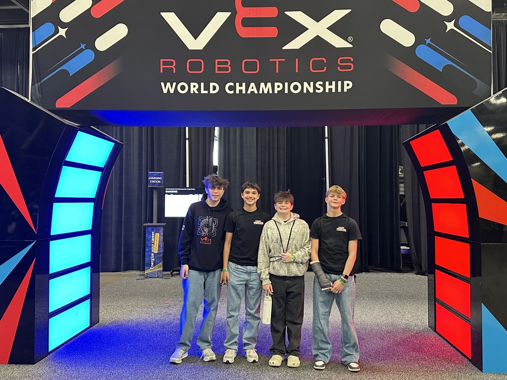 Four young men standing under a lighted archway that's red and blue.