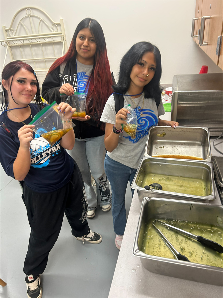 Three students holding ziploc bags filled with cucumbers being turned into pickles.