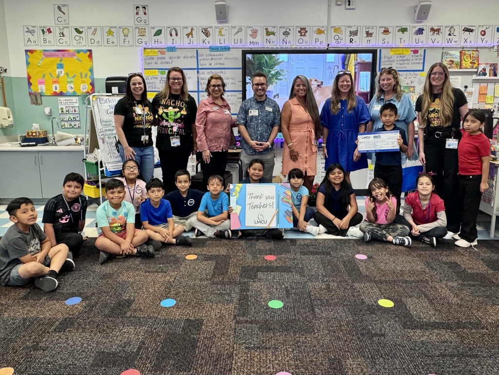 A class photo featuring a dual-language second grade teacher and students.