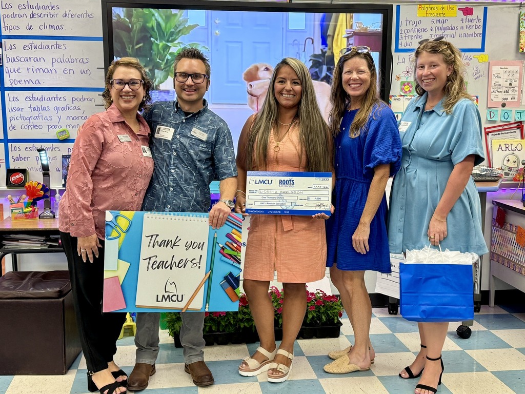 Representatives from LMCU present a teacher with a check for $1,000