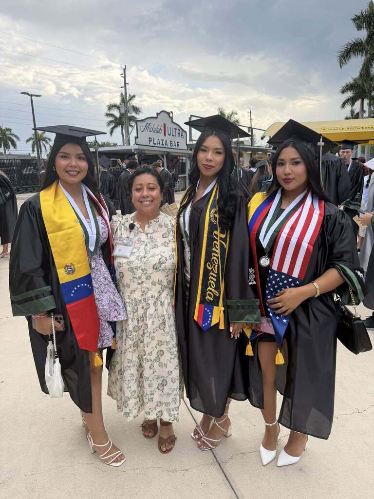 Young graduates with an adult mentor at a baseball park.
