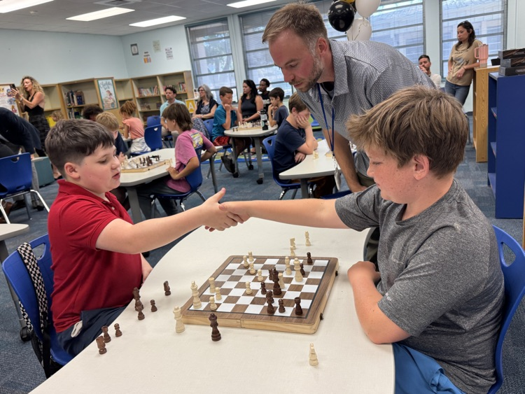 Elementary school aged chess players shake hands over a match