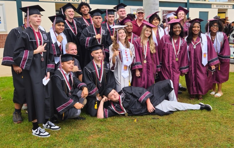 A GROUP OF HIGH SCHOOL GRADUATES POSE FOR A PHOTO BEFORE GRADUATION CEREMONY