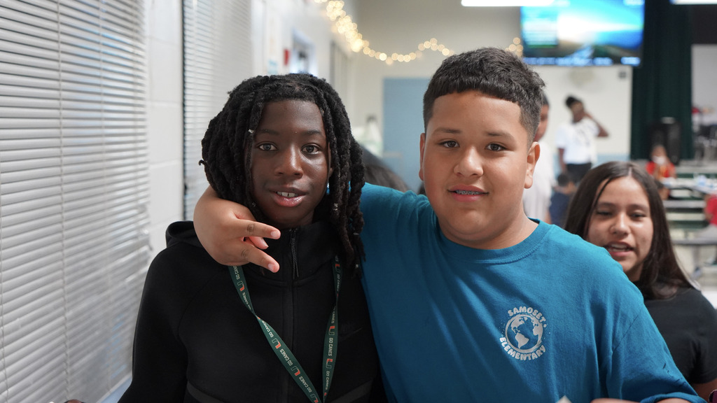 Two boys smiling in a school cafeteria.