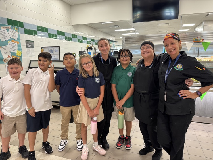 cafeteria staff poses with students as the first meals ever are served in a brand new school