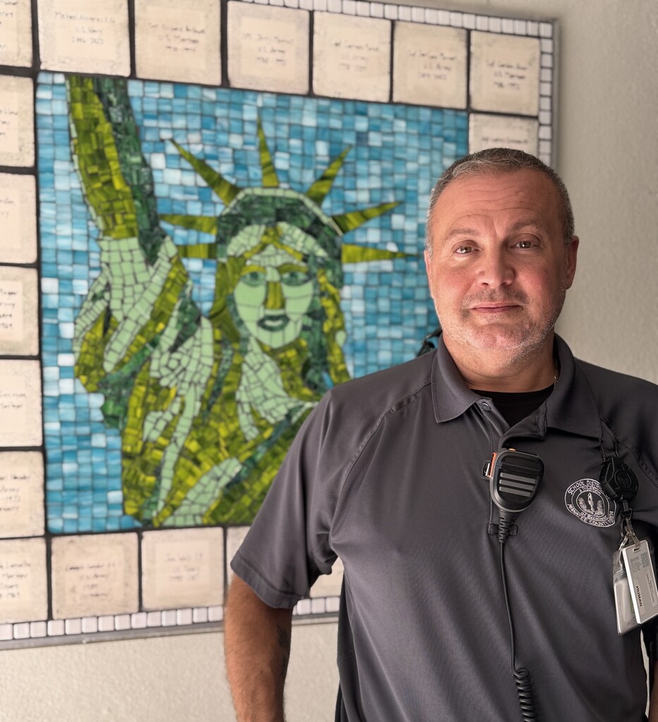 A school safety officer standing in front of a mosaic tile of the statue of Liberty