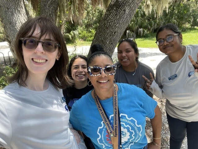 Women smiling outdoors in front of a tree