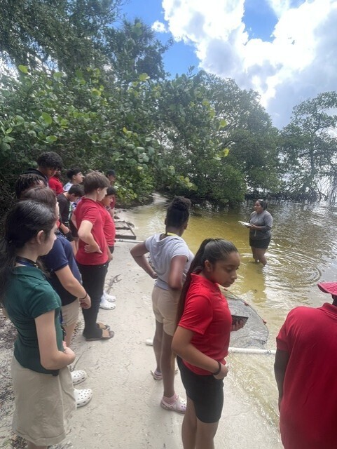 Students looking to an educator while outside near a body of water