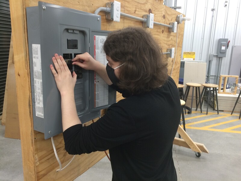 A student works on an electrical box in a construction classroom.