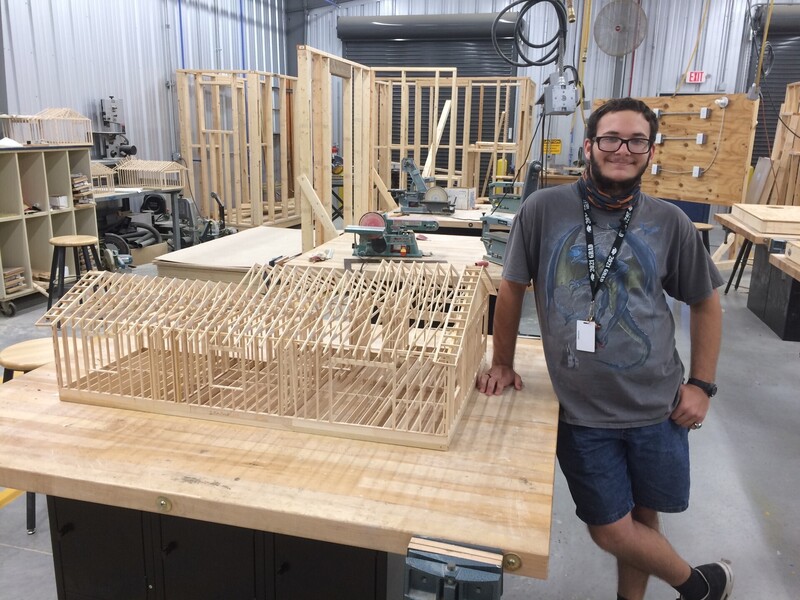 A student with a wooden structure in construction class.