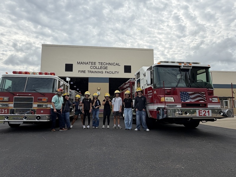 High school students wearing fire department helmets with clouds overhead.