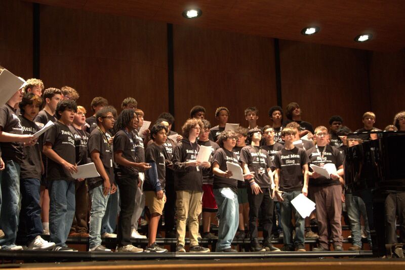 Young men standing on risers and singing as part of an all boys choir.