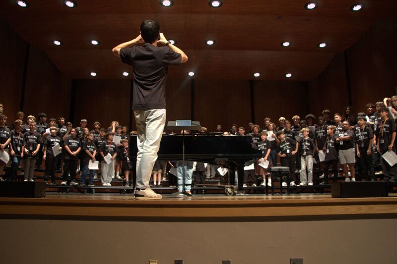 A man conducting a chorus standing on risers.