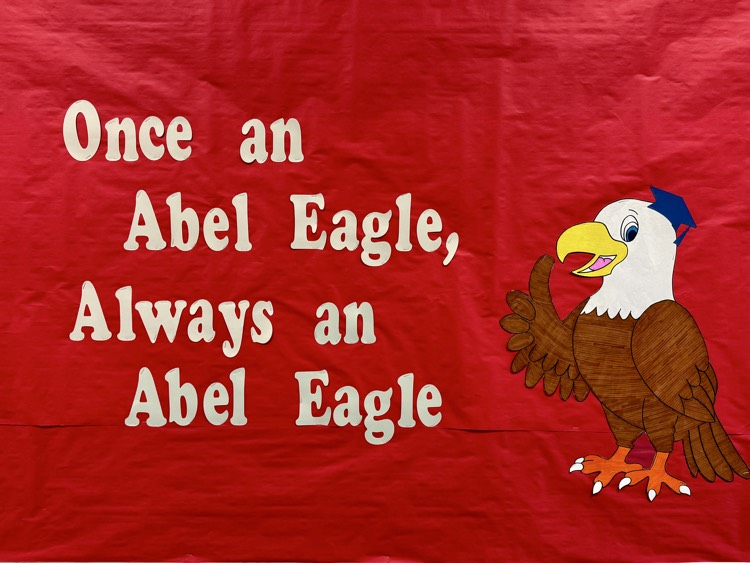 A sign hanging from a school wall reads once an eagle always an eagle