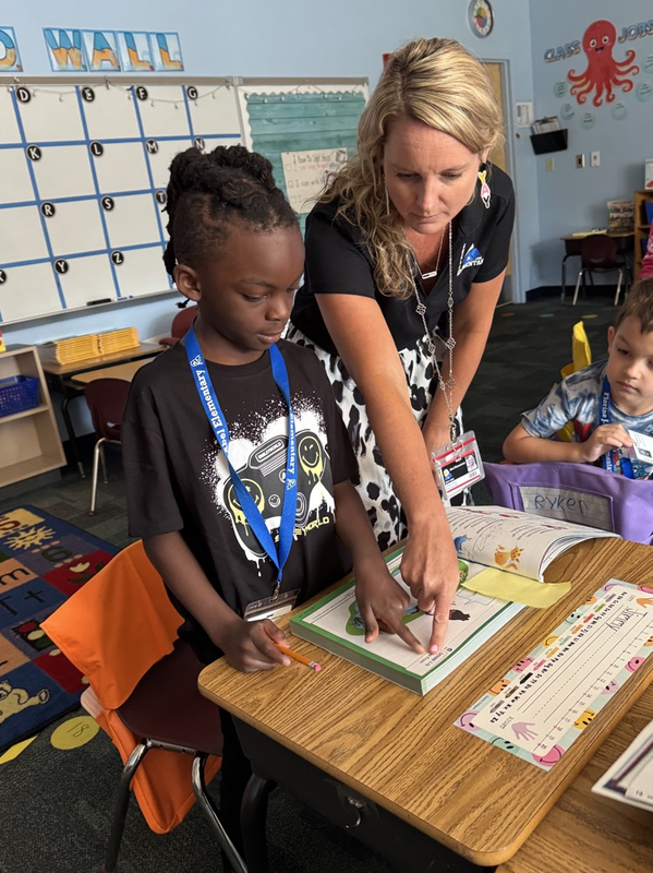 A teacher pointing out a lesson for a student in a math book