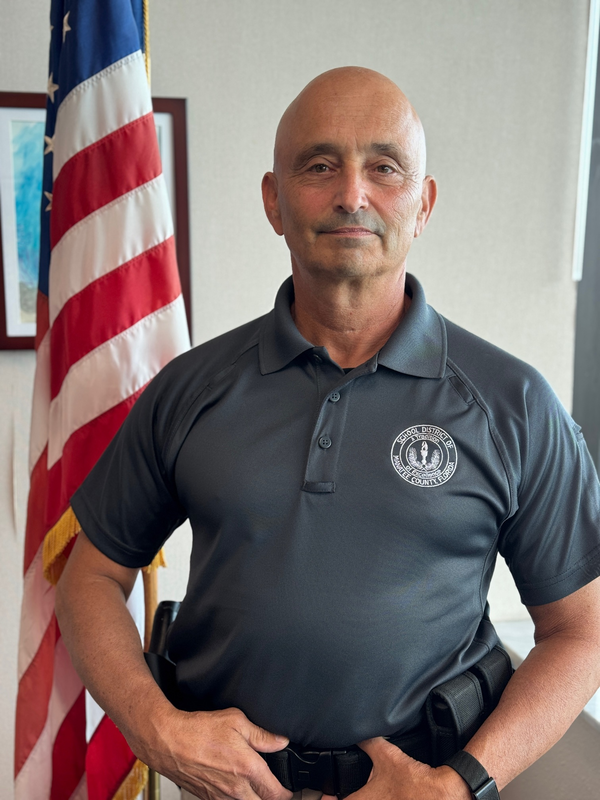 A school safety guardian stands by an American flag 