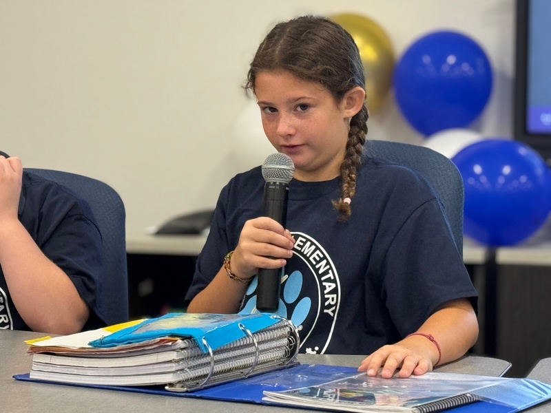 A young girl with pigtail braids holding a microphone.