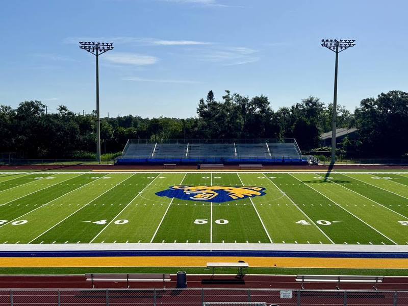A brand new turf field at Bayshore High School with a bright yellow and blue bear at center.