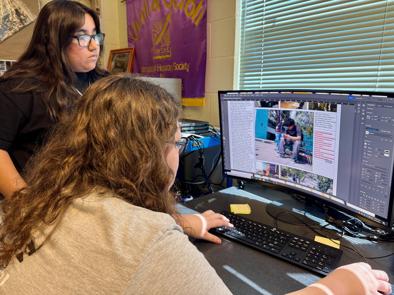 Two students work to edit the final version of their Paw Print newspaper
