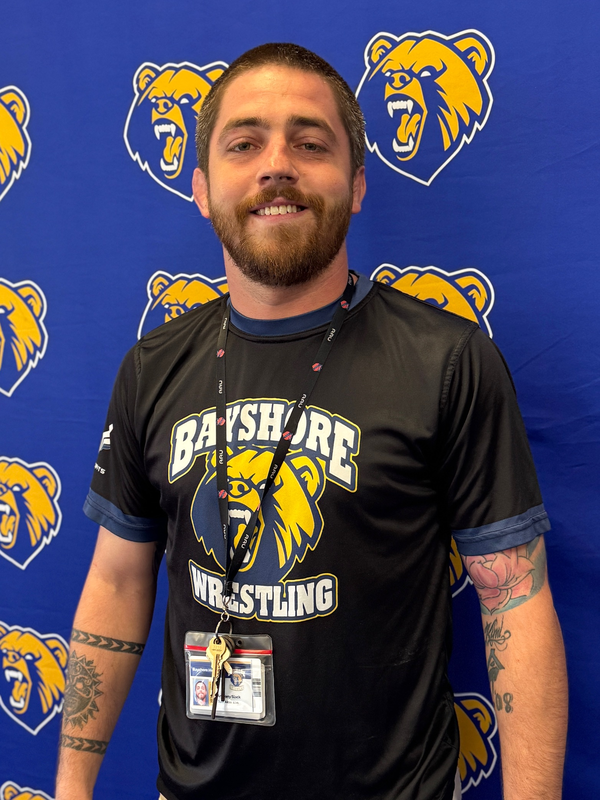 A smiling wrestling coach wearing a Bayshore Wrestling tshirt.
