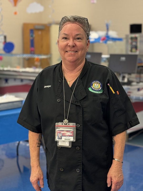cafeteria manager wearing black uniform smiles
