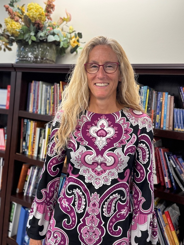Kim Sheffield, a district employee, standing in front of a bookcase at the Professional Support Center