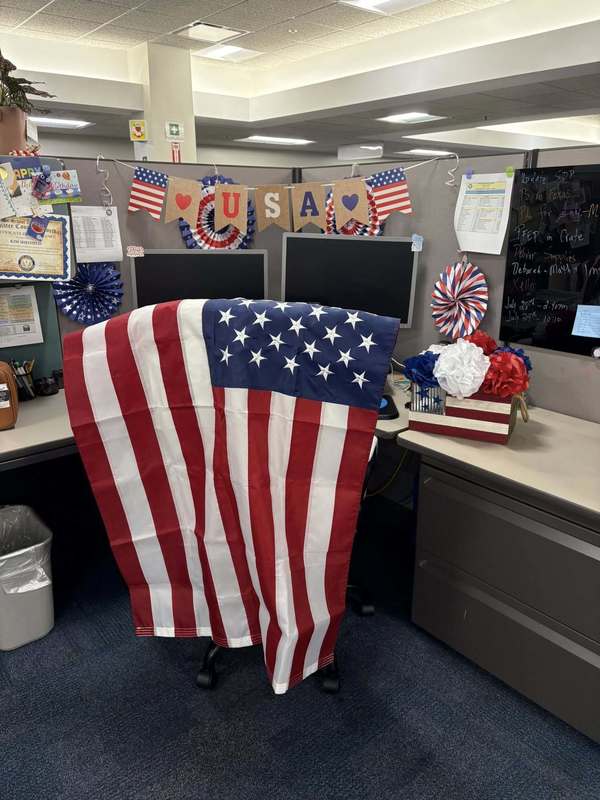 A cubicle with flags and red, white and blue decor, along with an American flag draped over a chair.