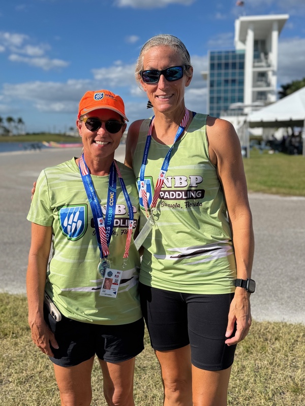 Two women smile while wearing NBP Paddling shirts