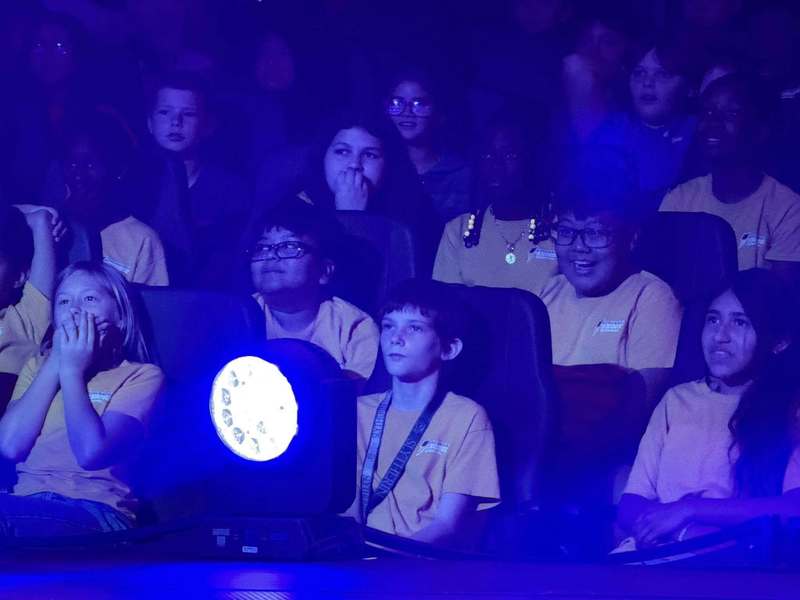 The facial interactions of surprise and happiness as students sit in the audience of a circus performance.