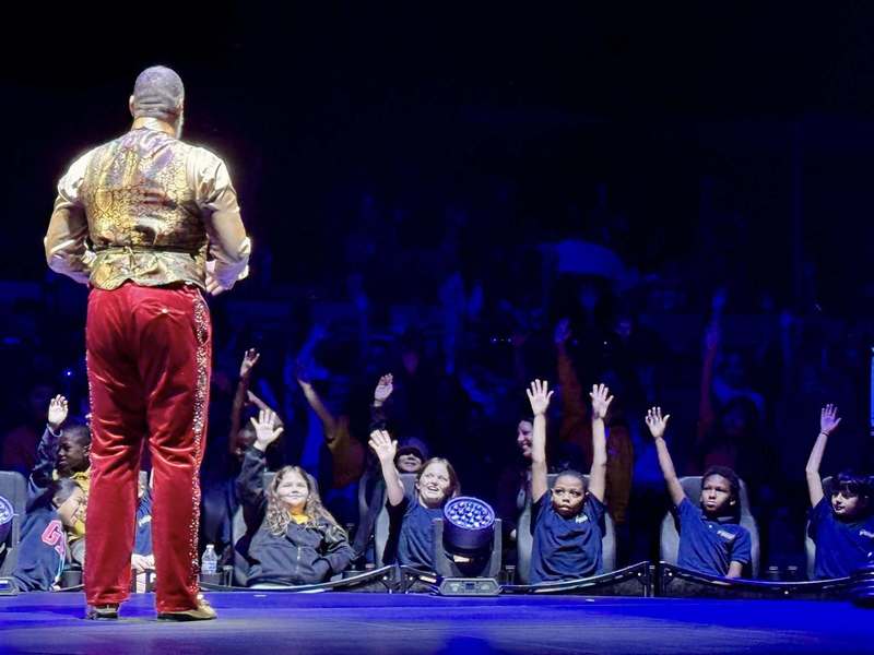 A ringmaster speaks to children who are raising their hands at the Wonderland circus at UTC in Sarasota.