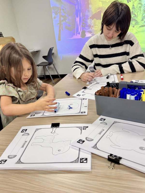 A high school senior doing an art project alongside her former teacher's child.