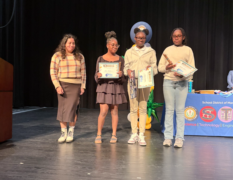 Students receiving an award and holding a certificate.