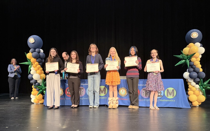 Students holding certificates on stage.