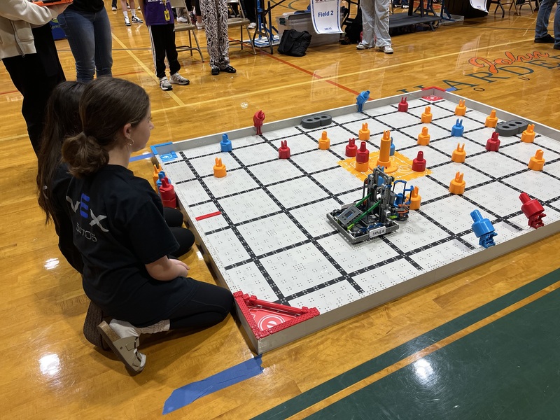 Students kneeling down while competing in a VEX robotics competition